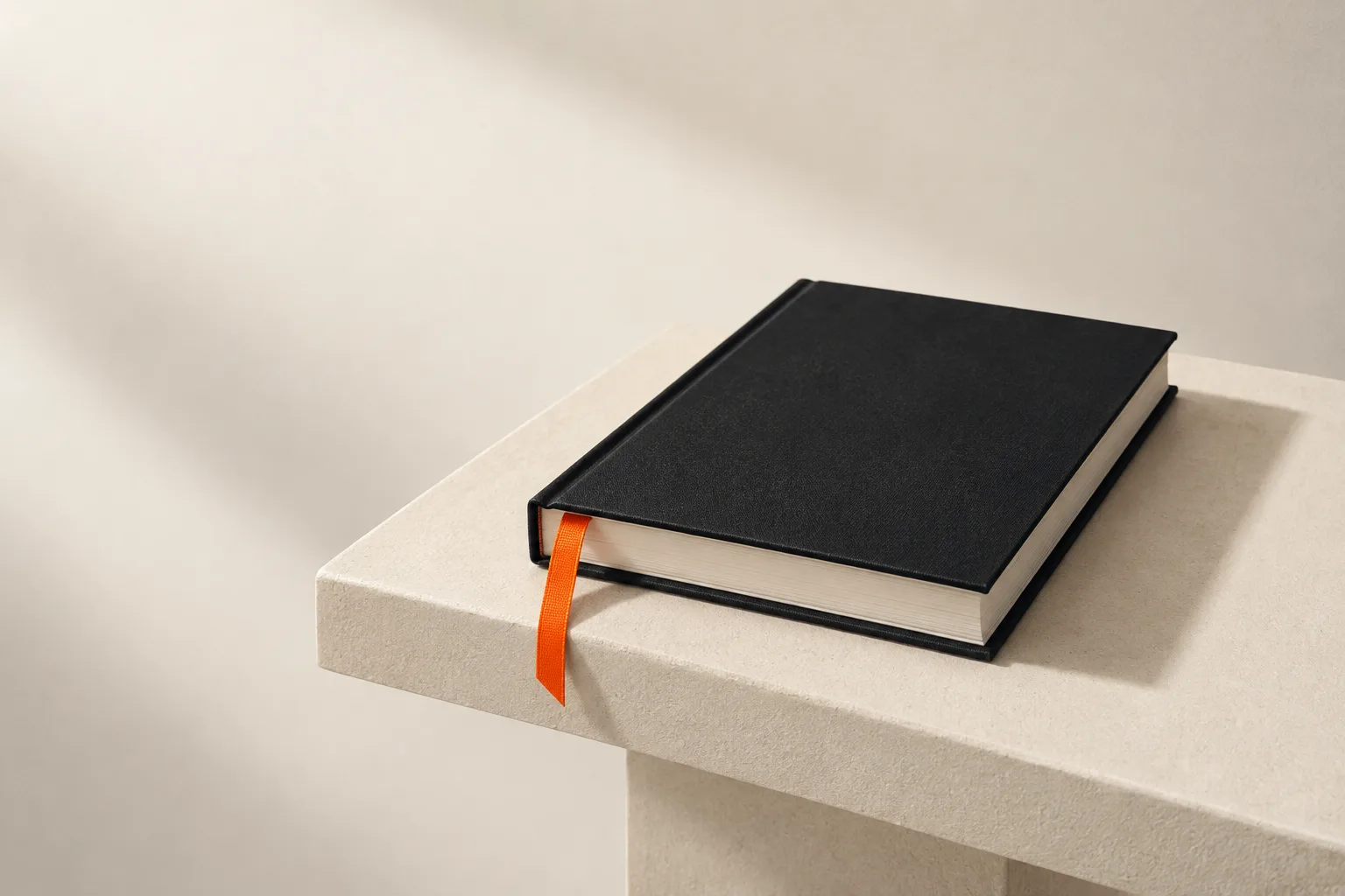 A black book with an orange ribbon on a stone plinth.