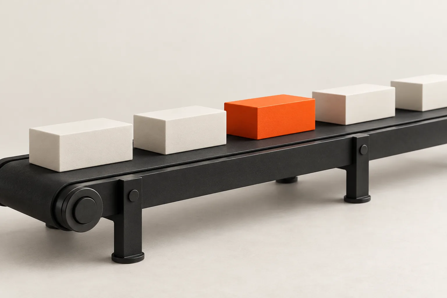 A black conveyor belt carrying white blocks and one orange block.