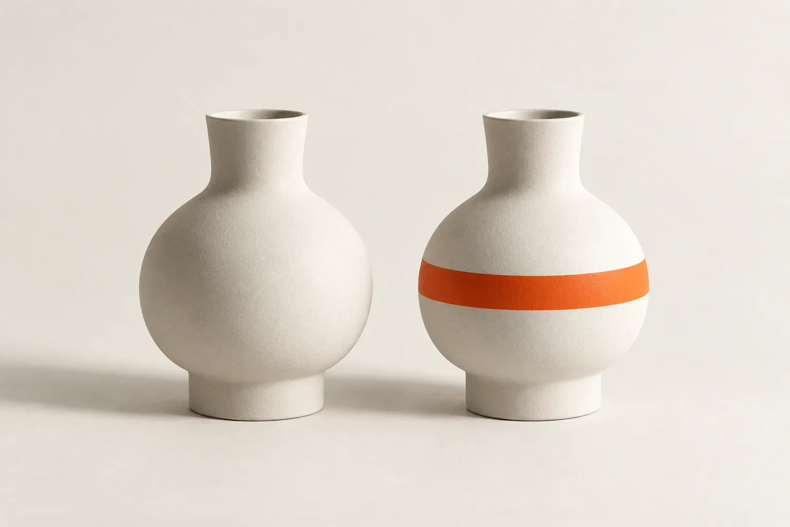 Two white vases side by side, one with an orange band.