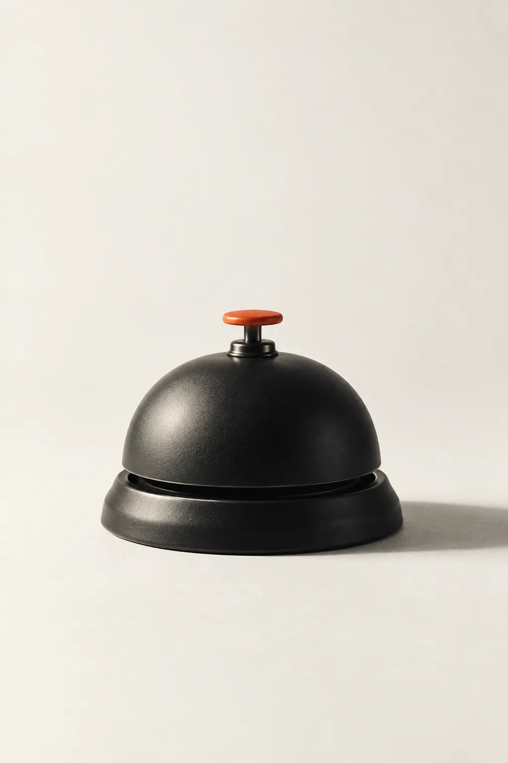 A black service bell with an orange button.